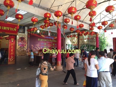 ผู้คนภายในวัดจีนที่ประดับด้วยโคมไฟสีแดงจำนวนมาก